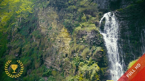 Picturesque Waterfall Flowing Down Rocky Green Cliffside