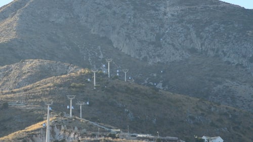 Gondolas Ascending Mountain in Urban Environment