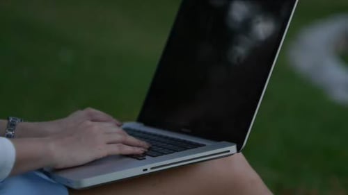 Young Adult Typing on Laptop Computer Outdoors