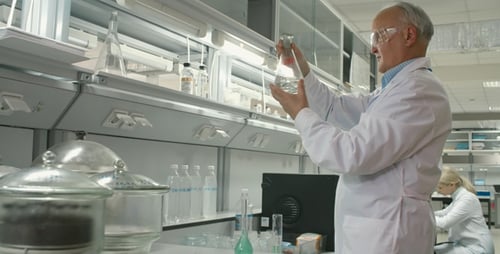 Senior Scientist Examining Glassware in Laboratory