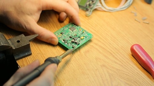 Repairing Circuit Board with Soldering Iron on Wood Surface