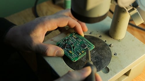 Electronics Repair with Soldering Iron on Circuit Board