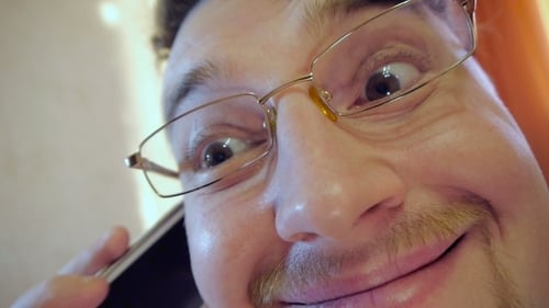 Extreme Close-Up of Smiling Face with Eyeglasses on Phone