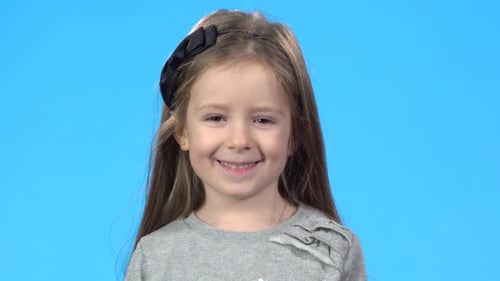 Little Blonde Girl Is Looking at the Camera and Laughing.