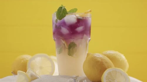 Refreshing Lemonade with Ice and Mint on Yellow Background