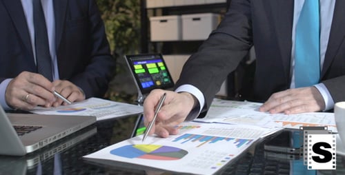 Businessmen Analyzing Charts and Graphs in Office