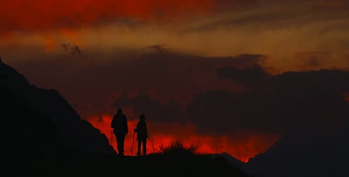 Silhouetted Couple Hiking at Dramatic Sunrise