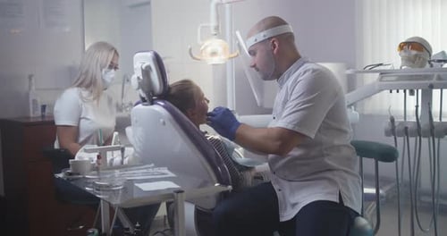 Professional Dentist Curing Teeth of Teen Girl