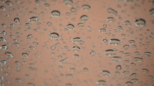 Regentropfen rutschen in einem Glas nach unten