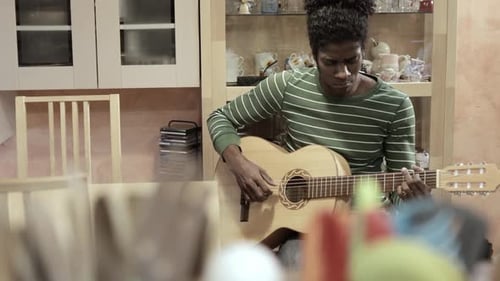 Young Adult Playing Acoustic Guitar at Home