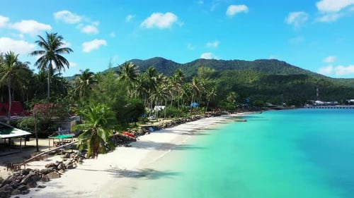 Paradise beach with palm trees bent over white sand washed by calm clear water of turquoise lagoon o