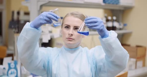 Woman Scientist Examining Blue Liquid in Beakers