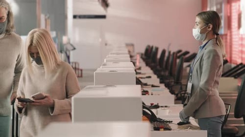 Travelers Check In at Airport Counter Wearing Masks