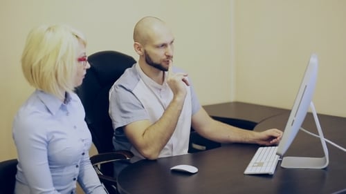 Adults Discussing Computer Screen in Office Setting