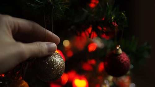 Decorating Christmas Tree with Golden Sparkling Ornament