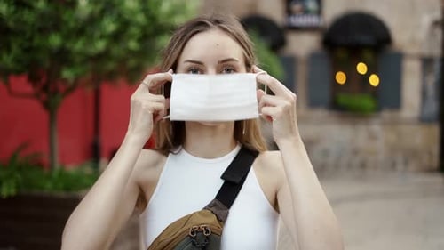 Woman Putting on Medical Mask for Coronavirus Protection Outdoors Front View