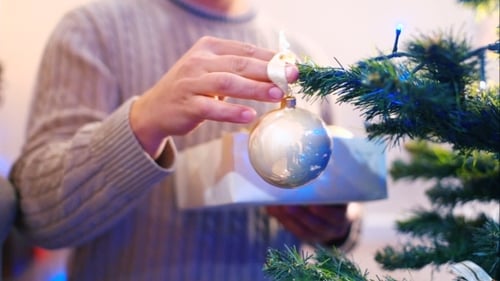 Person Decorating Christmas Tree with Ornaments