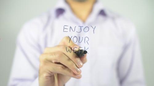 Hand Writes "Enjoy Your Week" On Clear Surface