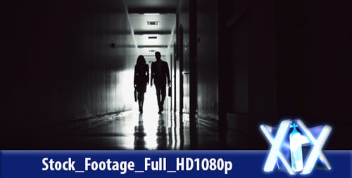 Two Figures Walking a Dark Hallway at Night