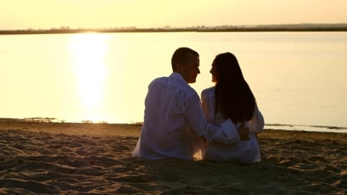 Couple In Love Sitting On River Bank