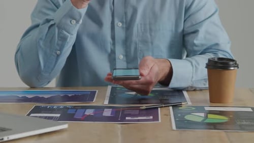 Business Person Using Phone at Desk with Charts