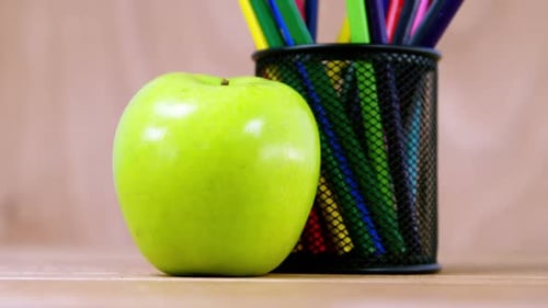 Green Apple with Colored Pencils on Wooden Table