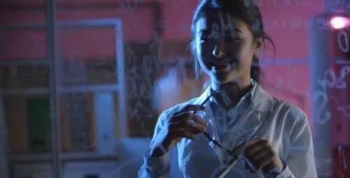 Young Scientist Writing Formulas on Glass in Lab