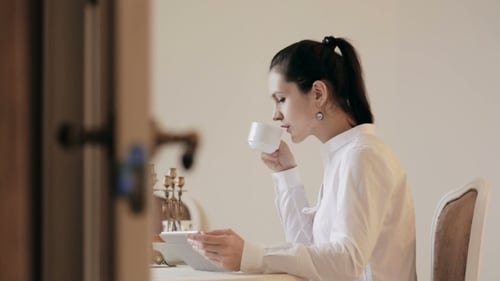 Woman Uses Tablet While Drinking Coffee Indoors