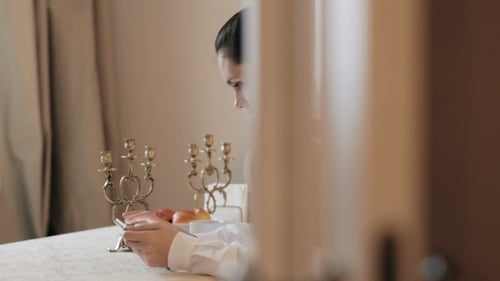 Young Woman at Table Looking at Phone