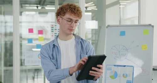 Guy in Casual Clothes which Working on Tablet Computer in Modern Office Room with Glass walls