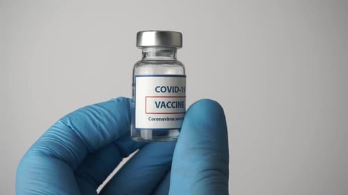 Gloved Hand Holds COVID-19 Vaccine Vial