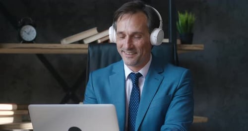 Man working at computer wearing suit and headphones