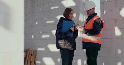Concentrated Engineers Discussing Examining and Developing at Construction Site
