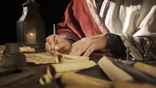 Person Writing with Quill Pen in Candlelight
