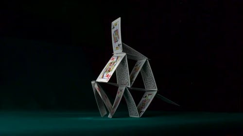 Collapsing House of Cards on Green Table