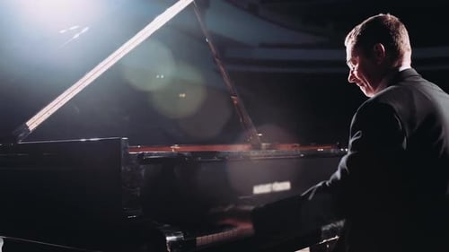 Pianist Playing Classical Piano on Stage in a Hall with Dim Lighting