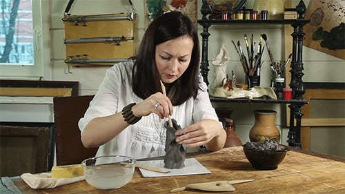 Woman Sculpting Clay Figure in Bright Studio