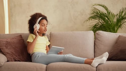 Girl Listens to Music on Tablet at Home