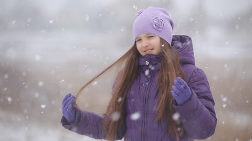 Schönes lächelndes Kind freut sich über Schneefall