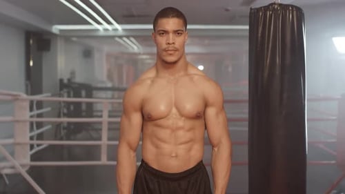 Kickboxing, Athletic Man Fighter Trains in Boxing Gym, a Muscular Man Takes a Fighting Stance