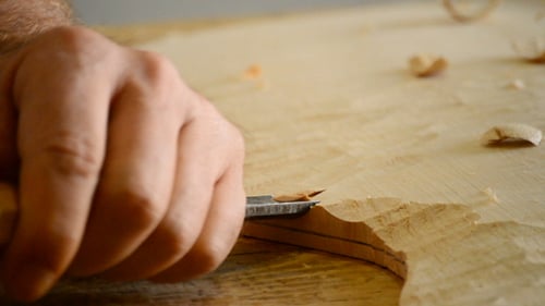 Luthier Manufacturing a Guitar with a Chisel in Workplace