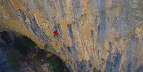 Rock Climber Ascends Steep Cliff Face in Mountains