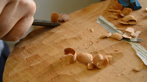 Luthier with a Chisel Working in a Guitar