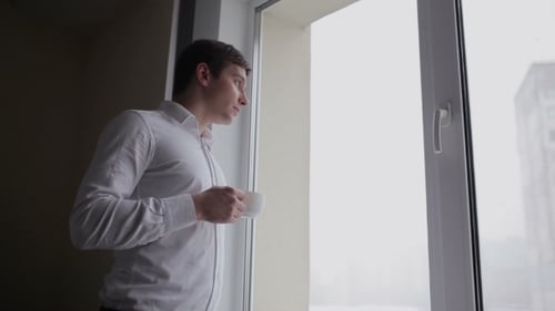 Young Adult Drinking from Cup by Window