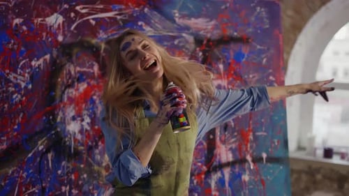 Femme dansant dans un studio d'art à Slowmo faisant semblant de chanter à la bombe aérosol