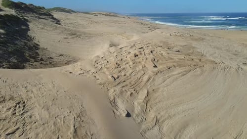 Drohne fliegt von Sanddünen am Strand weg