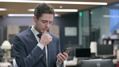 Attractive Businessman Using Smartphone in Office