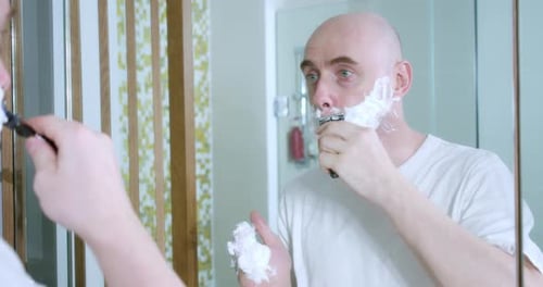 Young Man is Shaving Using Disposable Razor in Bathroom Closeup Side View
