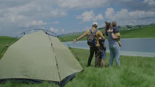 Back view of active travel family camping at the lake enjoying the leisure and freedom.