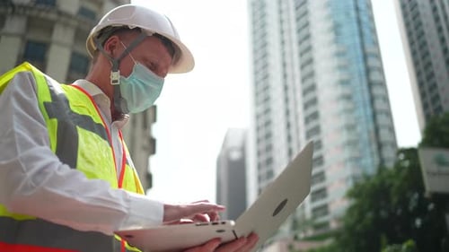 Engineer foreman worker with hard hat working with laptop at skyscraper construction site